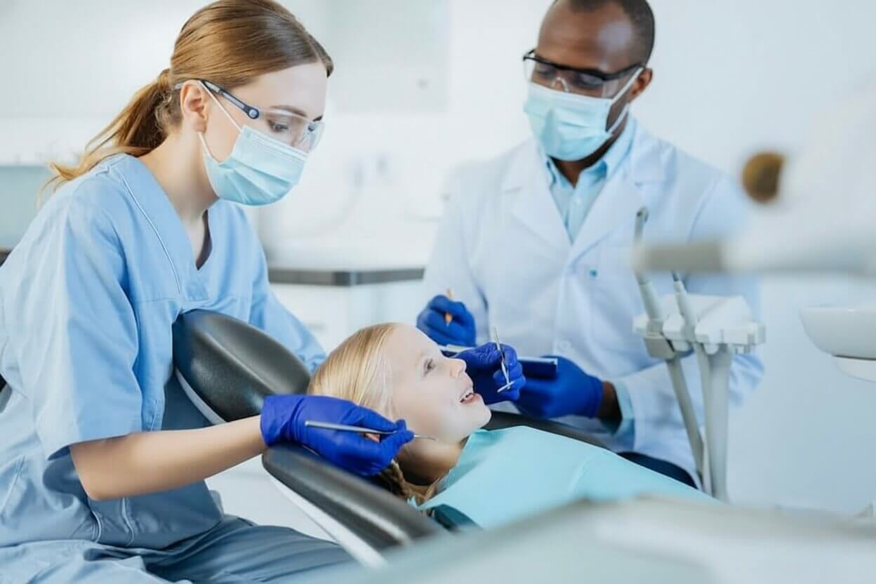 charming young medical student practicing oral cavity examination checking teeth little girl supervision professional dentist