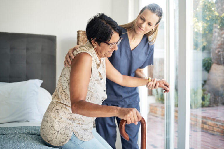 Blog 4 happy woman nurse patient elderly care support walking with stick old age home medical caregiver therapist helping senior person with disability retirement physiotherapy